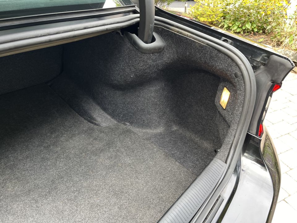 Open trunk of a black sedan showing carpeted cargo area