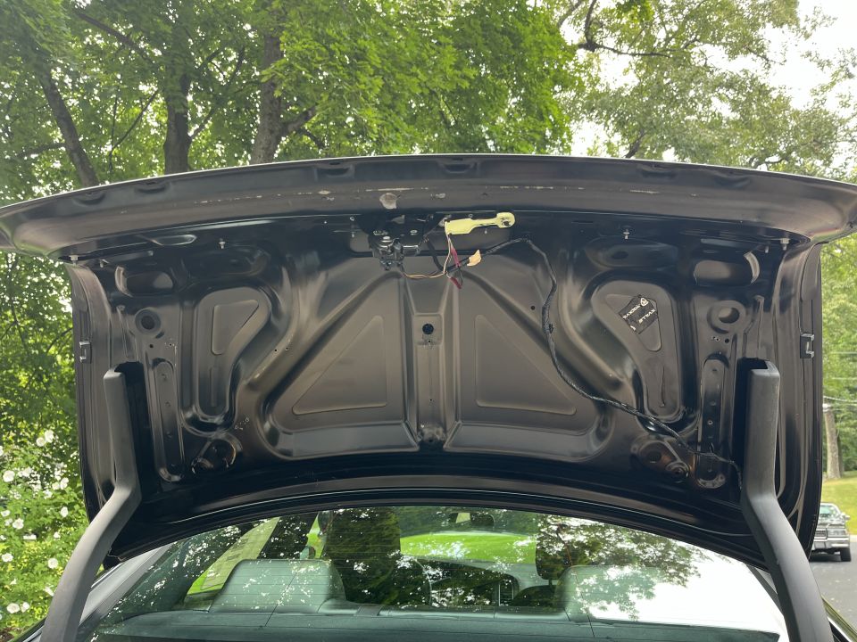 Underside of an open trunk lid on a black sedan