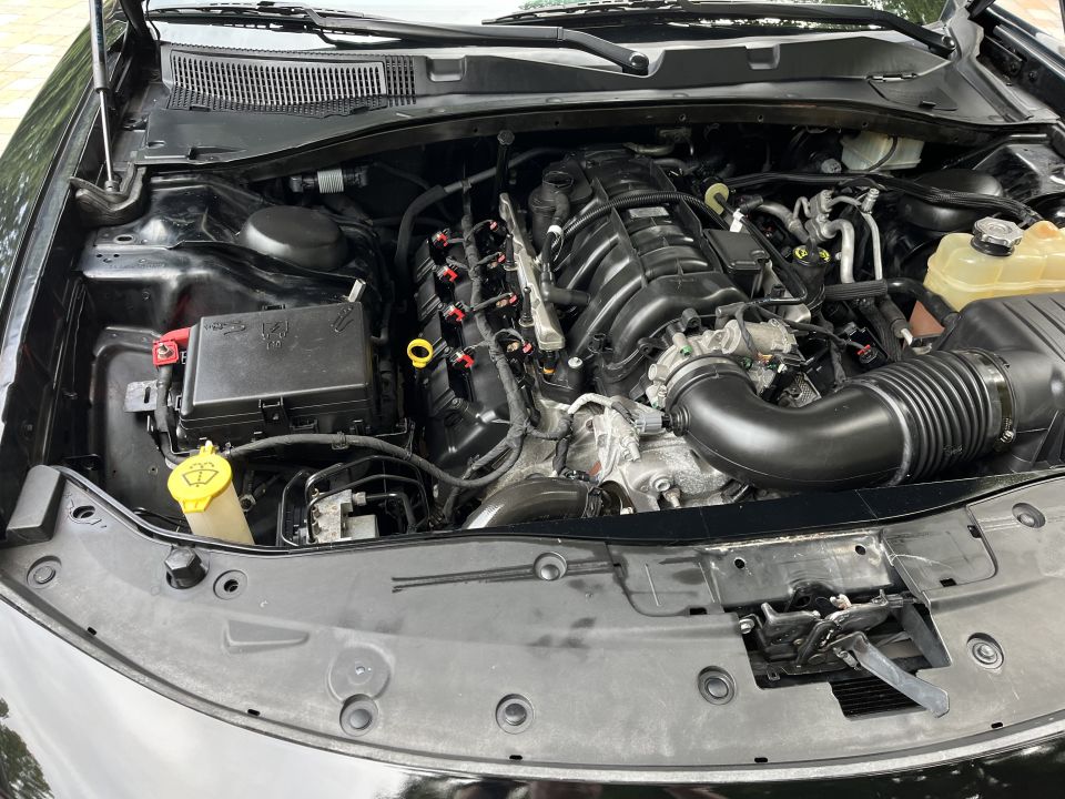 Engine bay of a black sedan with battery and air intake