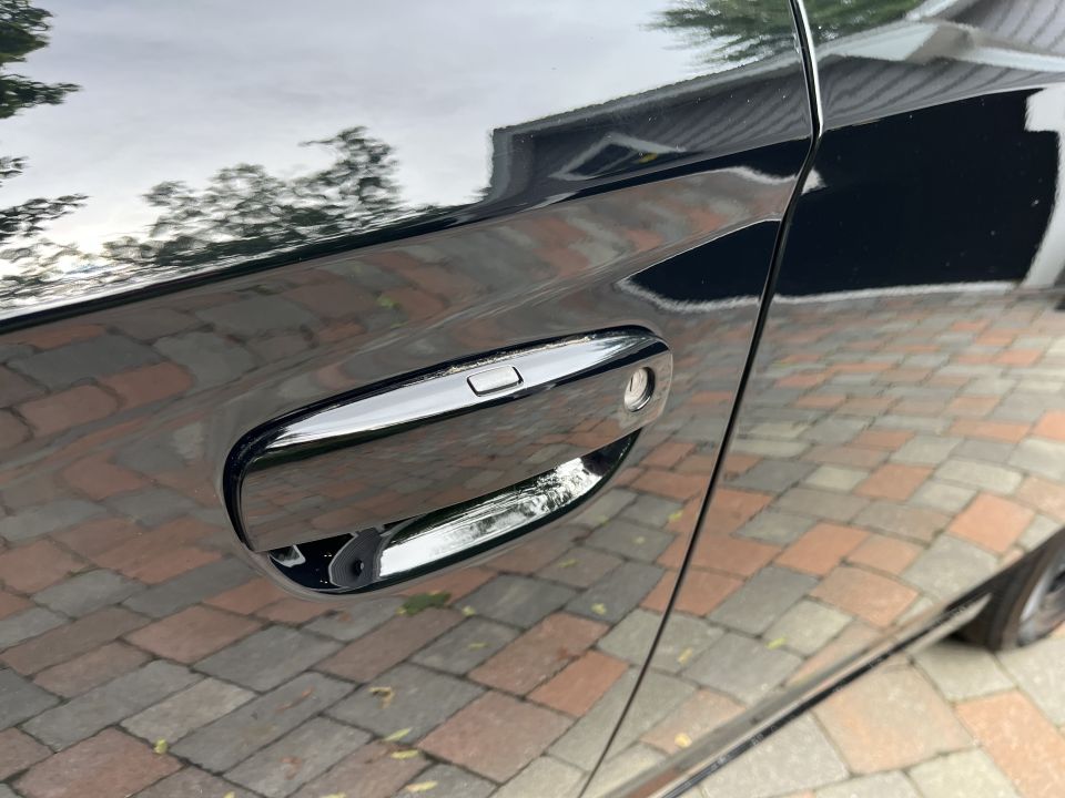 Close-up of a black car door handle with chrome trim