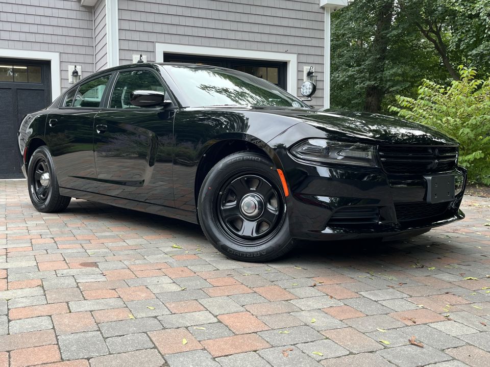 Black Dodge Charger side profile parked on paver driveway