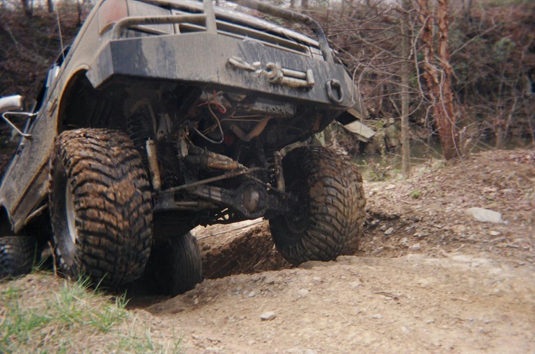 Muddy off-road vehicle with large tires going over rough terrain