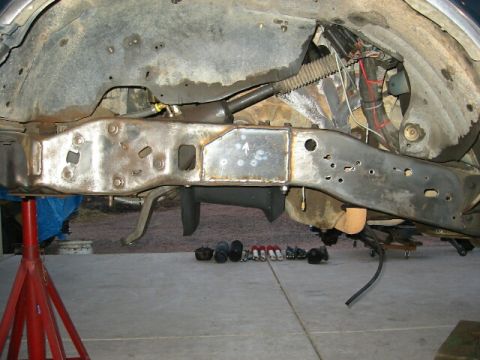 1994 Ford Bronco - Close-up view of a vehicle's frame undergoing repair, showing welded modifications and suspension parts laid out nearby.