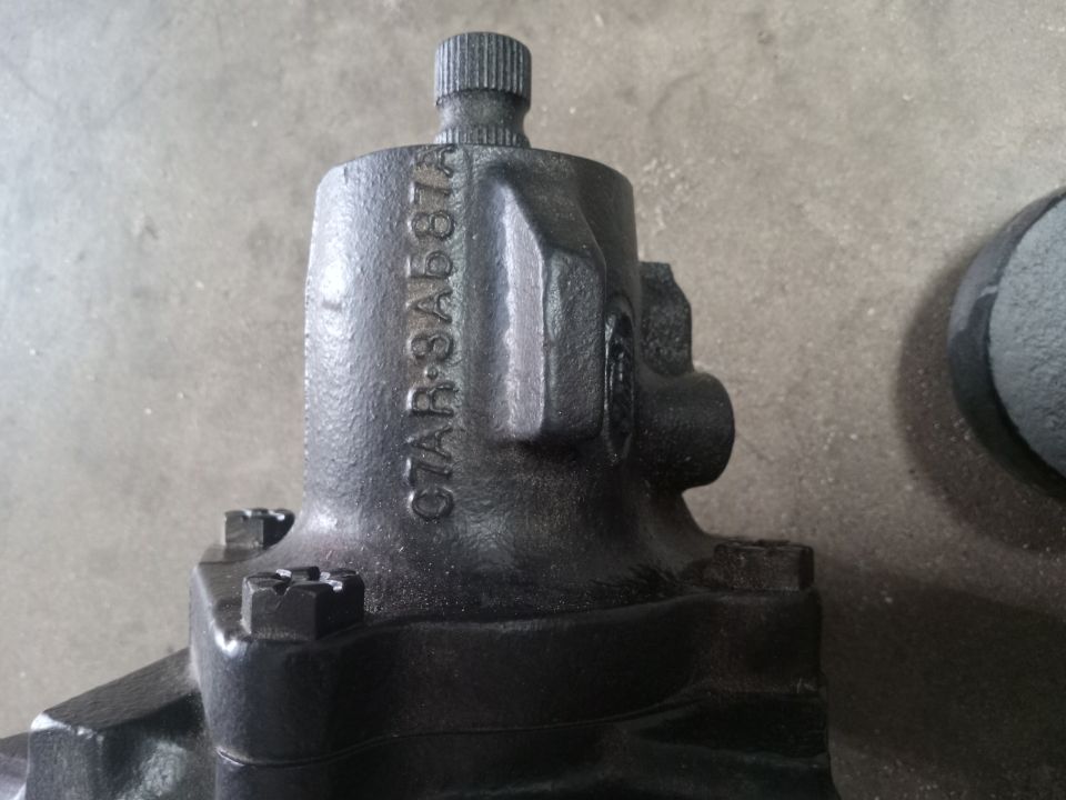 Black metal steering gear housing with embossed text C7AR-3A587A and splined shaft.
