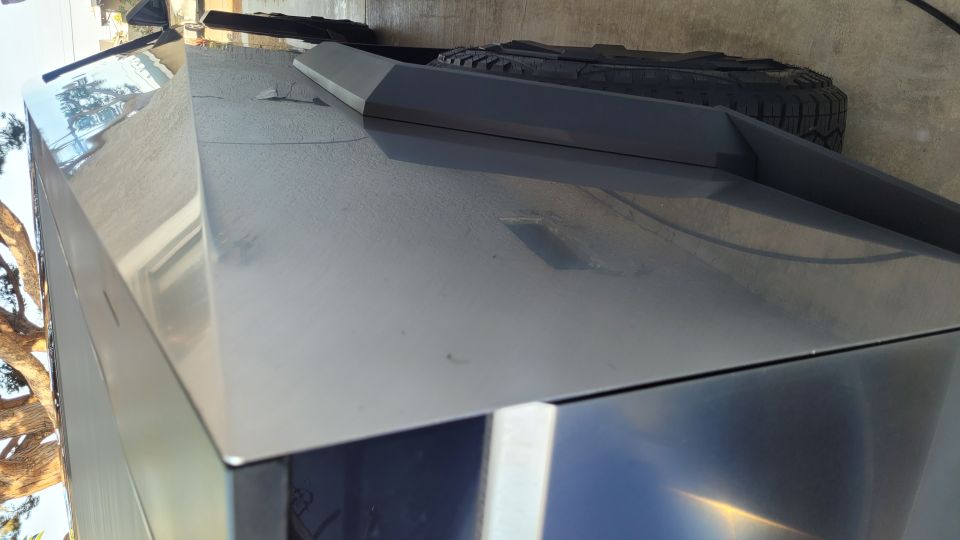 Close-up of stainless steel Cybertruck body panel with tire and trim