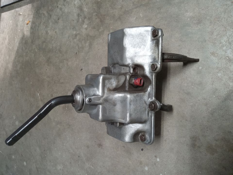 Silver transmission or transfer case assembly with two shafts on concrete.