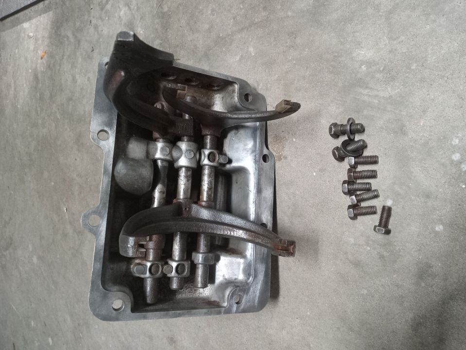 Disassembled gearbox housing with internal parts and bolts on concrete