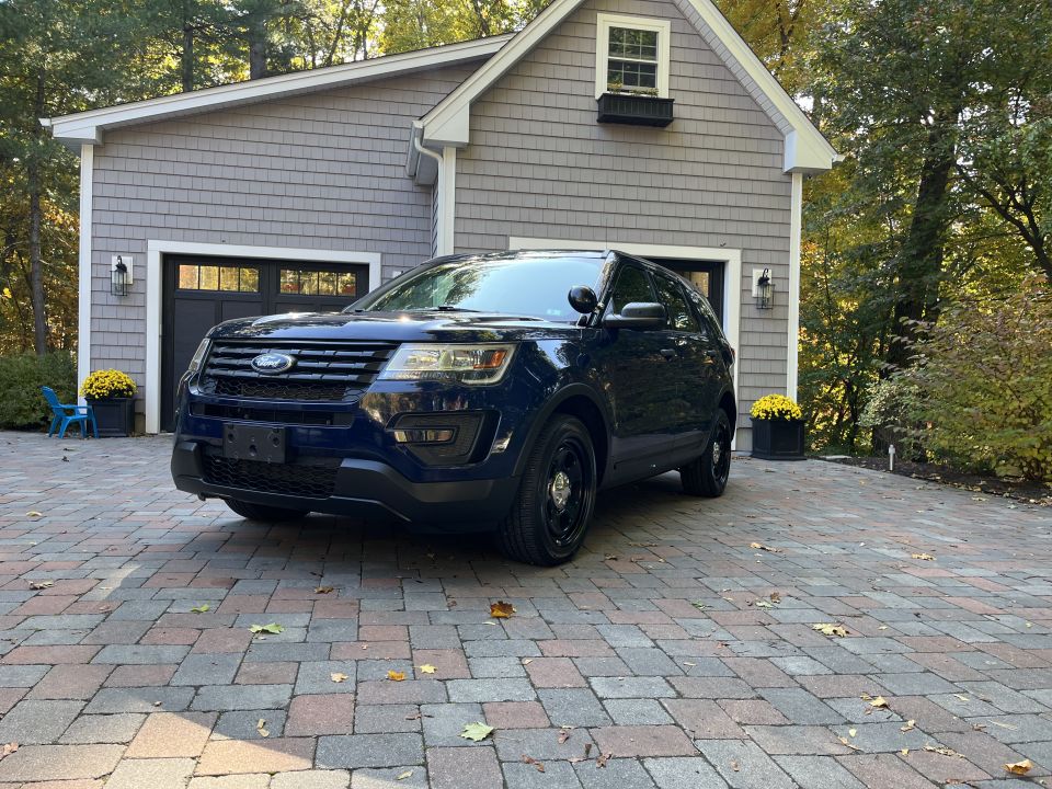 Dark blue Ford Explorer SUV front three-quarter view in front of a garage