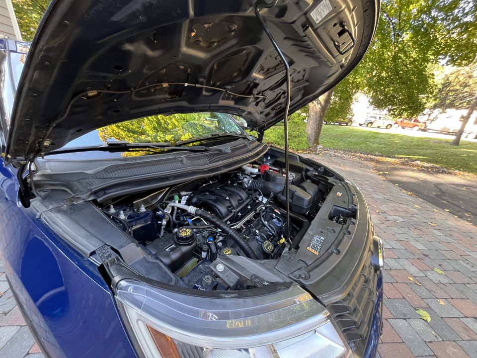 Open hood and engine bay of a blue Ford Explorer parked outdoors