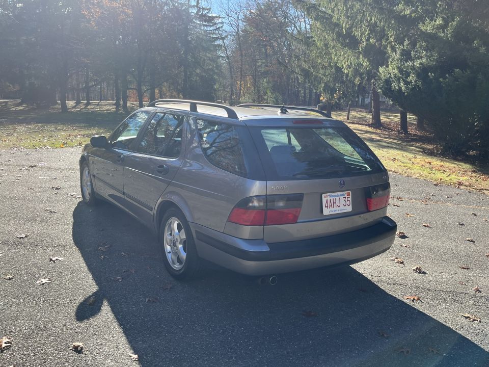 SAAB 9-5 wagon parked on asphalt with trees in background. License plate reads 4AHJ 35