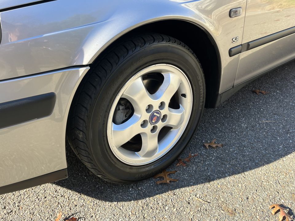Silver Saab 9-5 SE with a black trim strip and an 'SE' badge on the fender