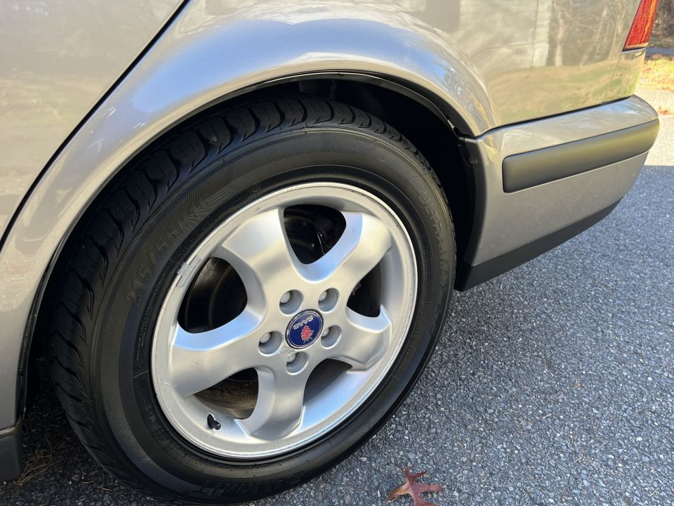 Silver car rear wheel with Saab logo and bumper detail