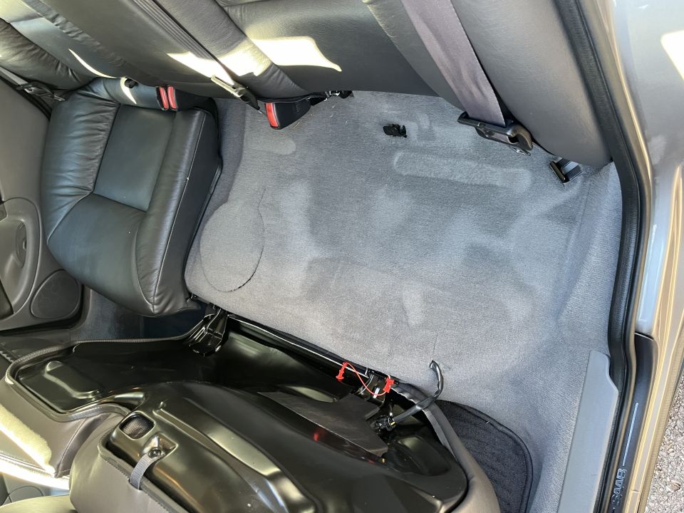 Interior rear seat and floor of a car with gray carpet and black leather seats