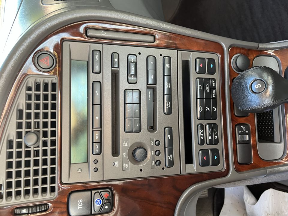 Car dashboard with wood trim, radio, climate controls, and gear shifter