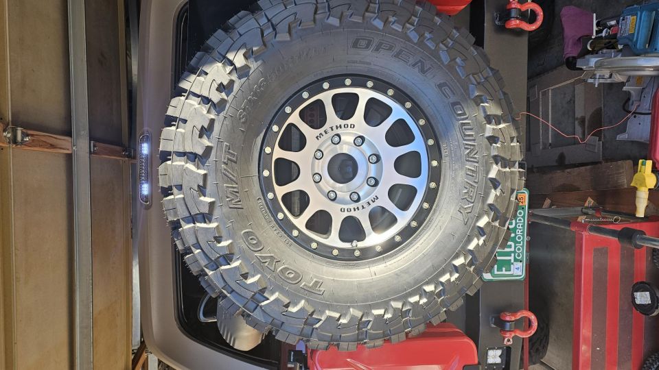 Spare tire on a Method wheel, mounted on the back of a vehicle. Colorado license plate visible