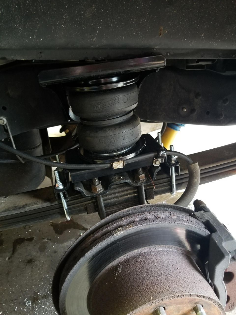 Close-up of air suspension helper bags installed on the rear axle of a truck, near the brake rotor