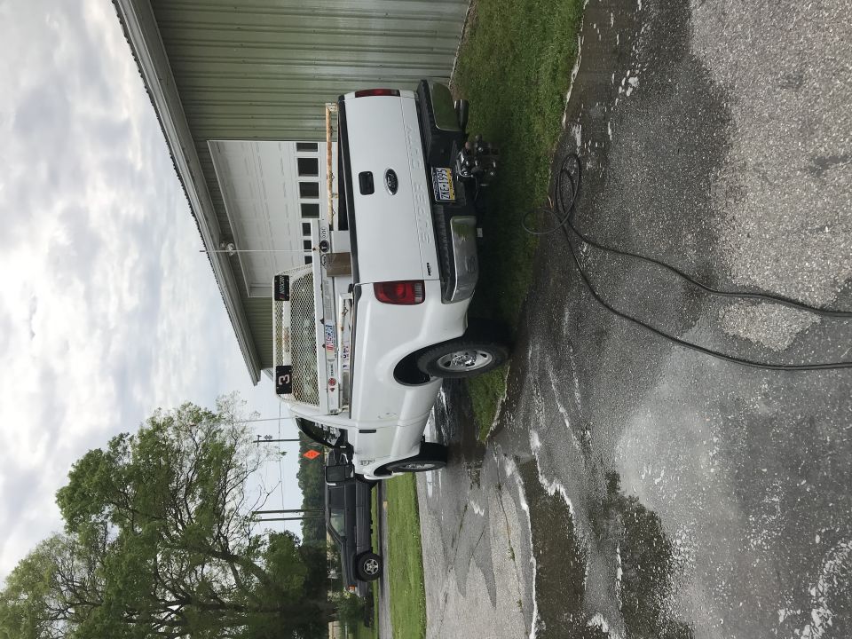 White 2008 Ford F-250 pickup truck with a utility bed, parked next to a building