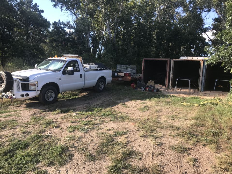 White pickup truck parked outdoors with trees and a small structure in the background