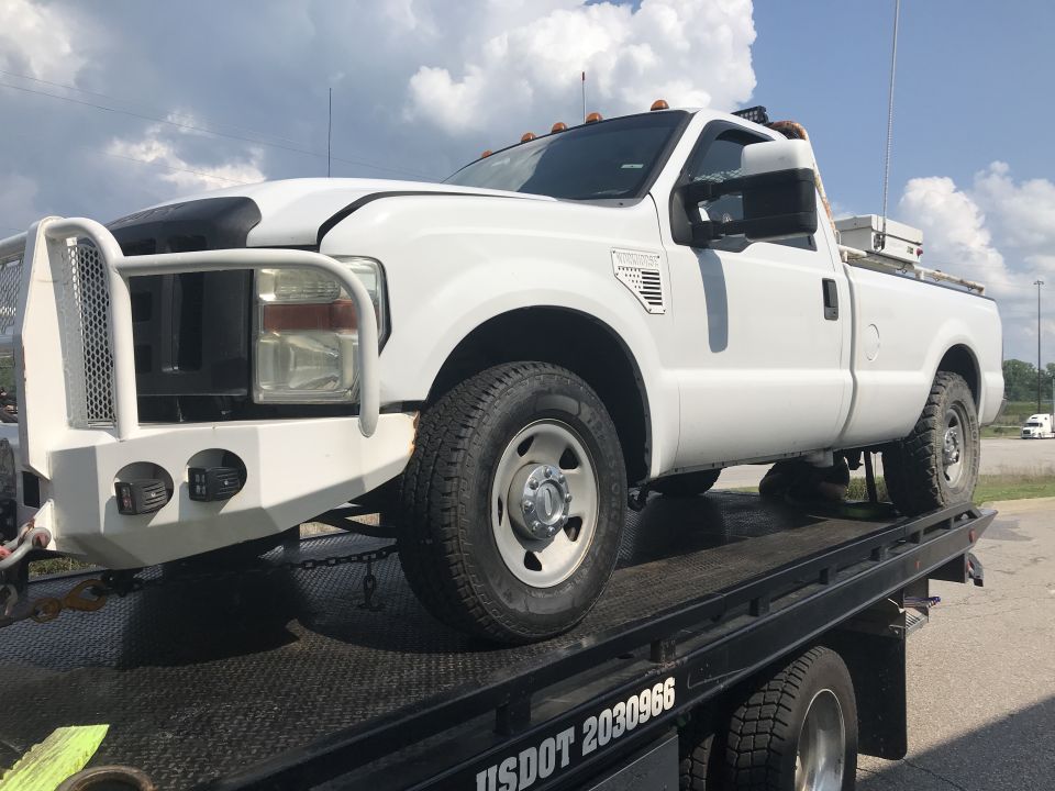 White 2008 Ford F-250 pickup truck on a trailer, 3q-front view