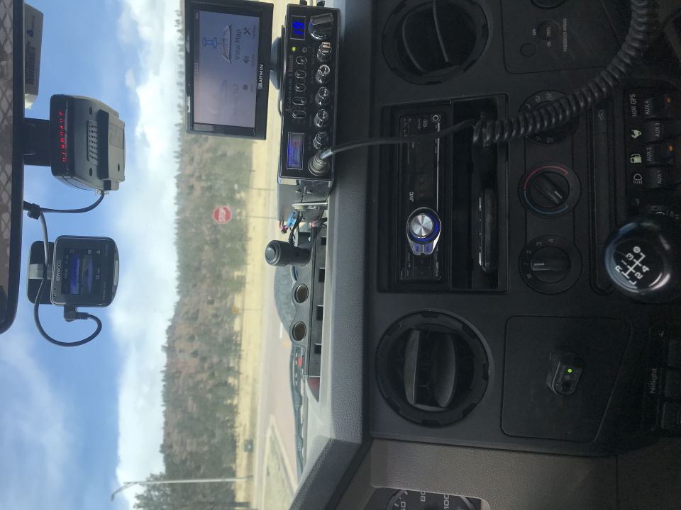 Truck interior dashboard with GPS, CB radio, stereo, and gear shifter.