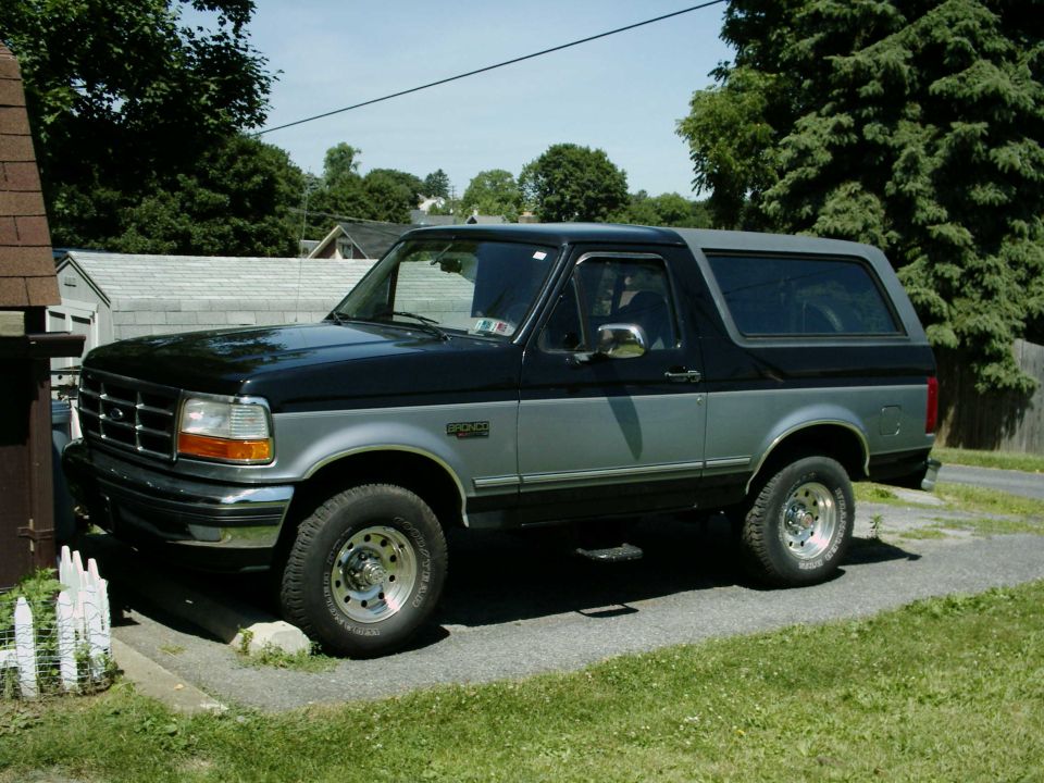 1990s Ford Bronco SUV, black and silver, parked on a driveway.