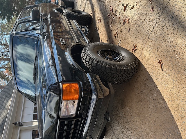 1987 Ford Bronco with aftermarket wheels and tires parked on a driveway