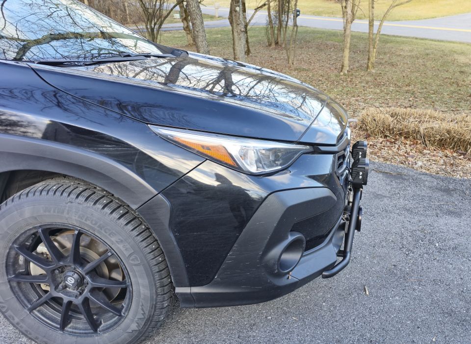 Black Subaru Impreza front corner with bull bar and auxiliary lights.