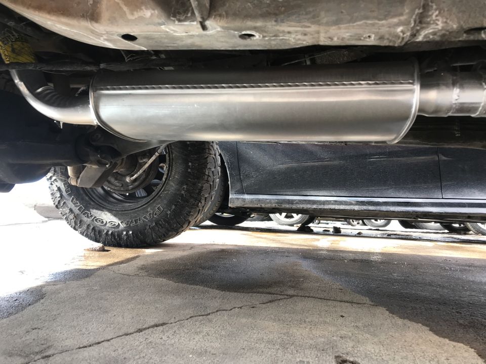 Underside of a vehicle showing exhaust system and tire.