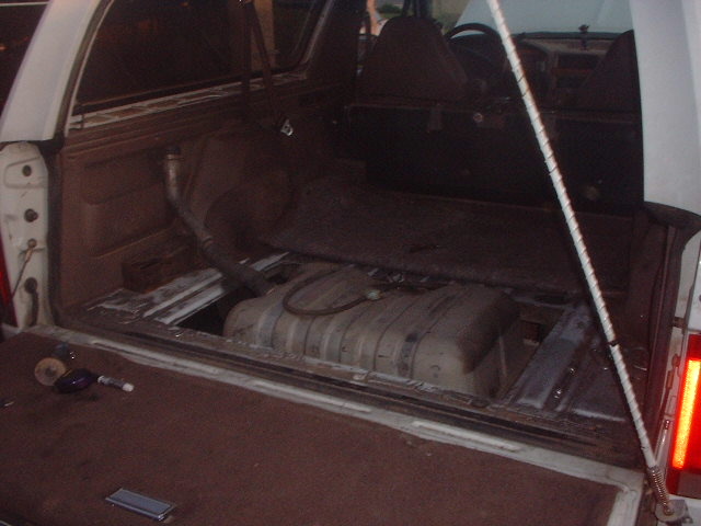 Cargo area of an SUV with rear seat folded showing fuel tank and floor brackets