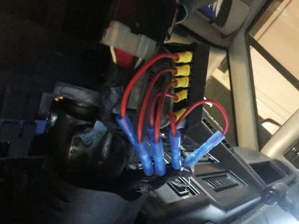 Vehicle fuse block with red wires and yellow fuse taps, blue butt connectors.