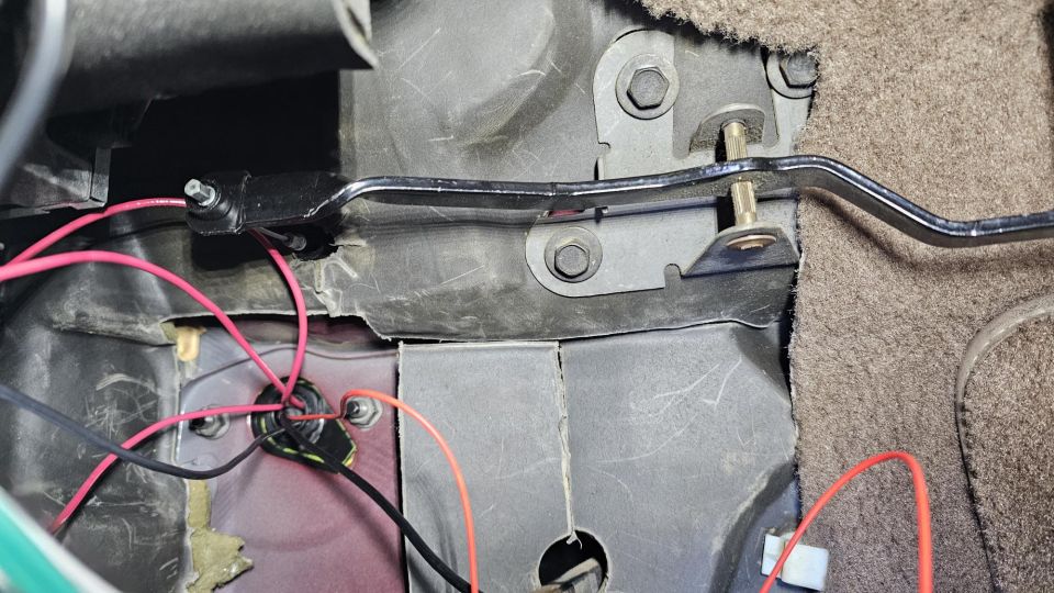 Close-up of wiring and a metal bracket under a vehicle dashboard.