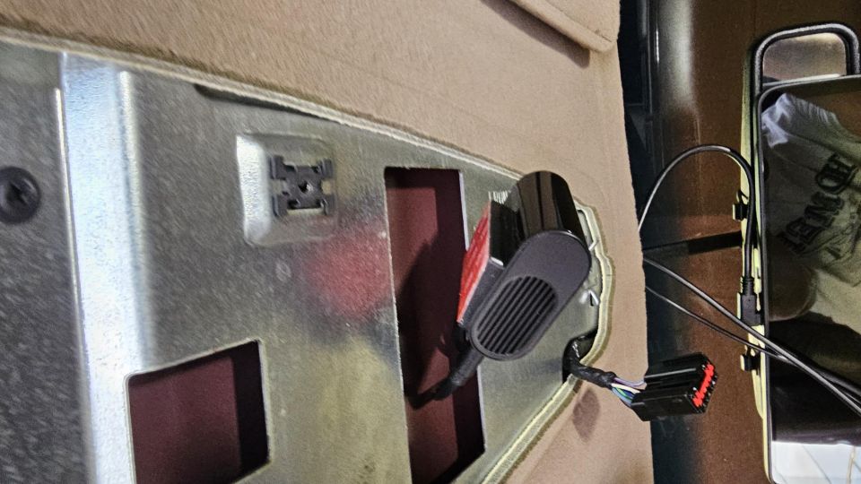 Interior vehicle panel with black electronic component and wiring.