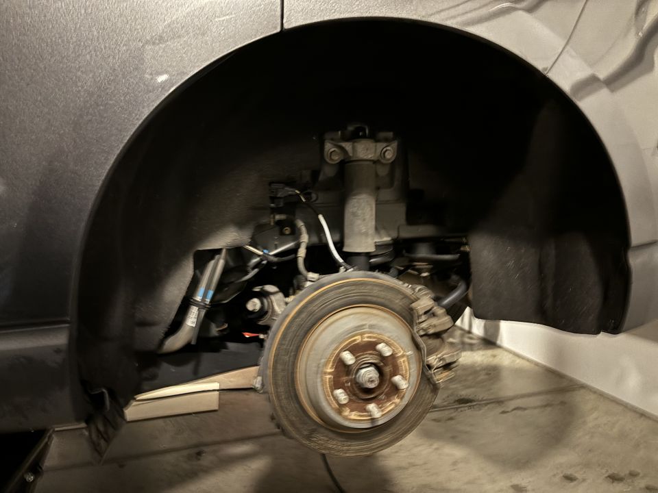 Rear wheel brake assembly with rotor and caliper visible inside wheel well