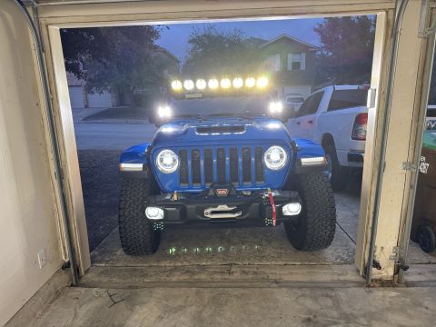 2022 Jeep Wrangler - A blue 2022 Jeep Wrangler is parked in a garage, equipped with a winch and a light bar on the roof.