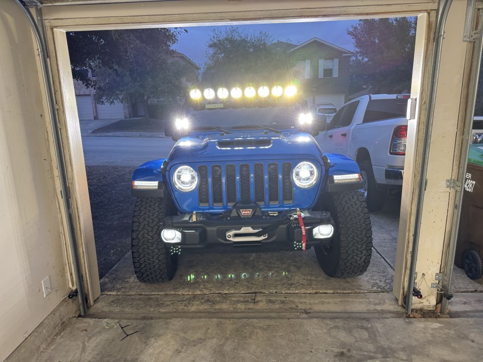 Blue 2022 Jeep Wrangler with winch and light bar parked in a garage, facing forward