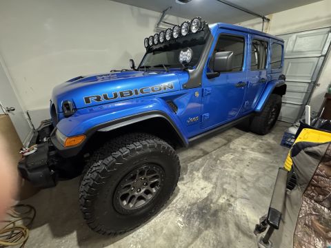 2022 Jeep Wrangler - A blue 2022 Jeep Wrangler Rubicon is parked inside a garage, equipped with off-road accessories.