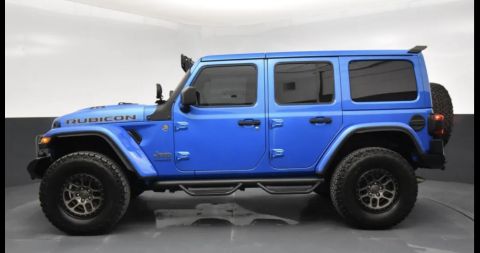 2022 Jeep Wrangler - This blue 2022 Jeep Wrangler is shown from the passenger side, highlighting its off-road features and modifications.