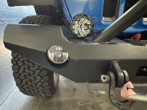 2022 Jeep Wrangler - Front bumper detail on a 2022 Jeep Wrangler, showing KC lights and off-road tire.