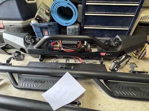 2022 Jeep Wrangler - Aftermarket Jeep Wrangler bumper and side steps are laid out on the floor.