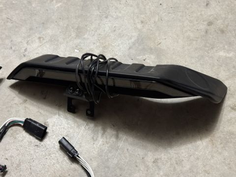 2022 Jeep Wrangler - A black automotive part with attached wiring is shown on a concrete floor.