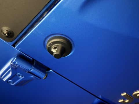 2022 Jeep Wrangler - Close-up view of a blue car's door hinge and latch mechanism, with visible text from a watermark at the bottom right.