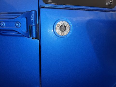 2022 Jeep Wrangler - Detail of a blue vehicle's door hinge and lock cylinder, with a Supermotors watermark.