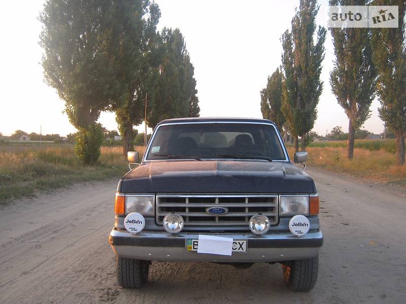 Dark blue 1988 Ford Bronco front view with aftermarket fog lights and a grille badge