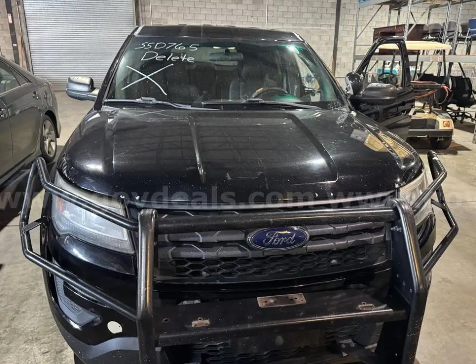 Black Ford Explorer PIU with push bar, windshield marked '55D765 Delete', parked in a warehouse