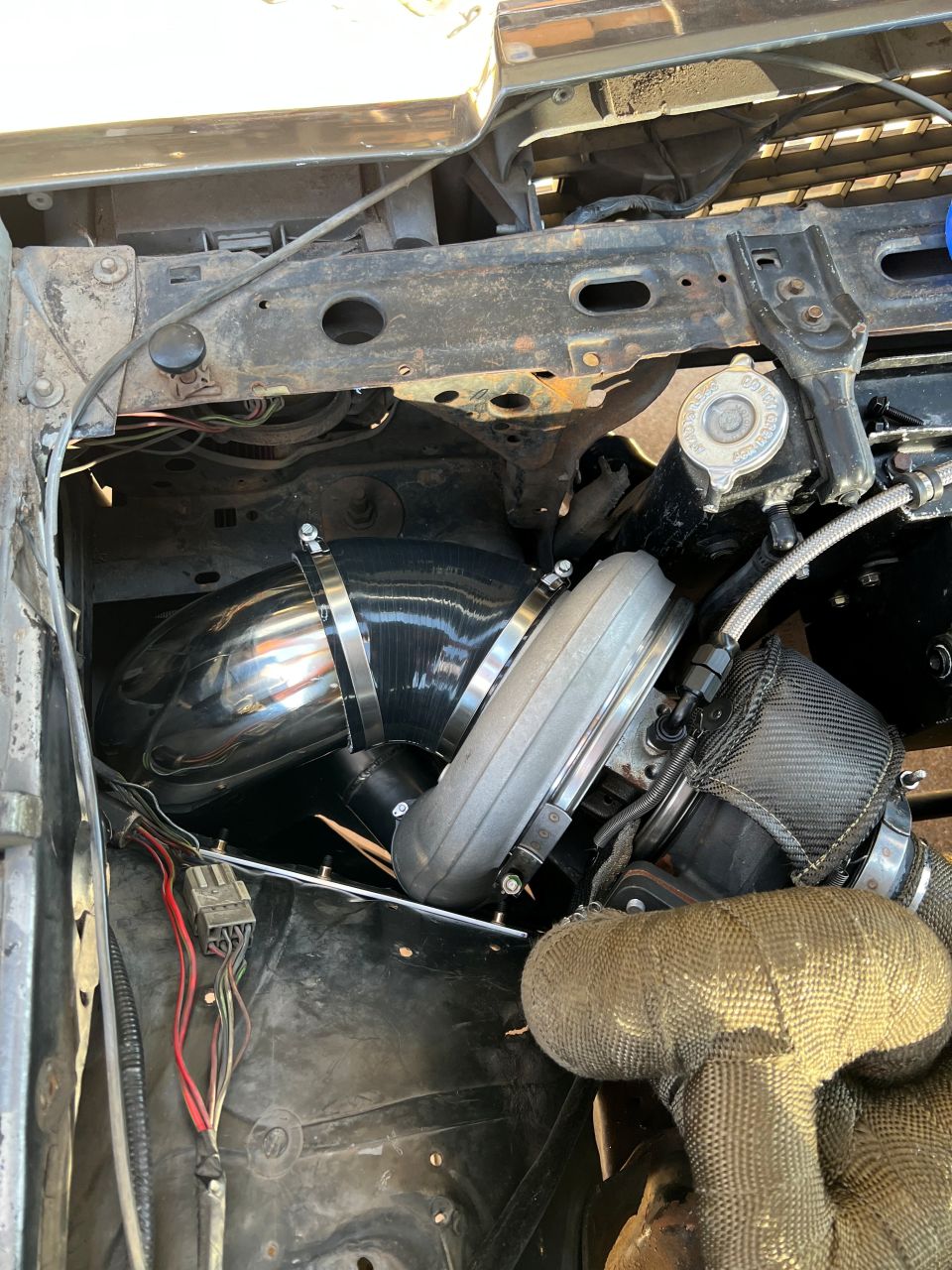 Engine bay with turbocharger, intake piping, and exhaust wrap.