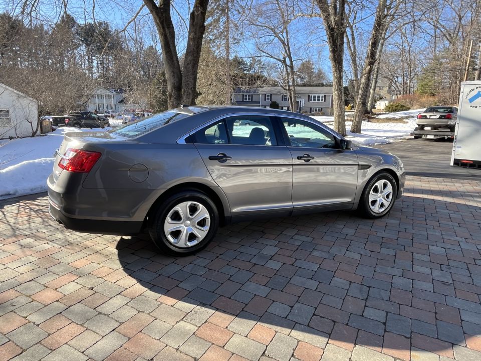 Passenger-side rear three-quarter view of a gray Ford Taurus sedan