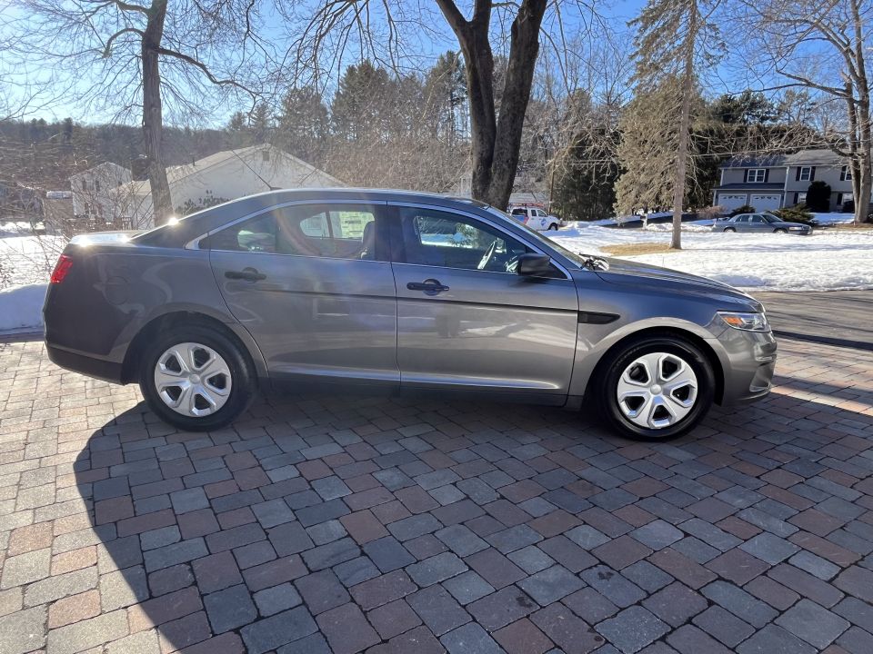 Passenger-side profile of a gray Ford Taurus sedan in a driveway