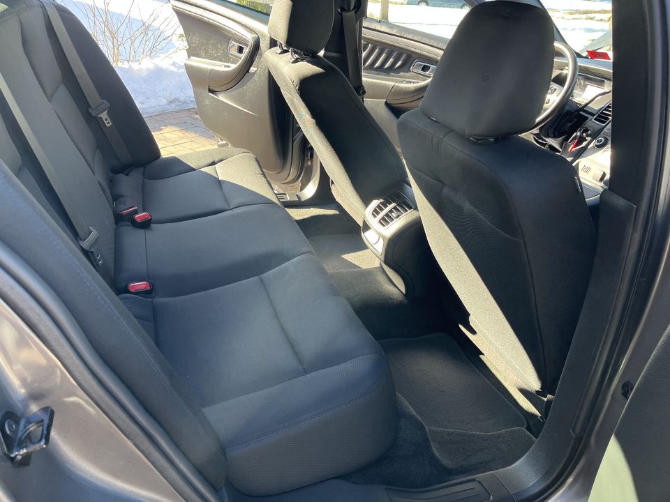 Rear bench seat and front seat inside a sedan, dark cloth upholstery