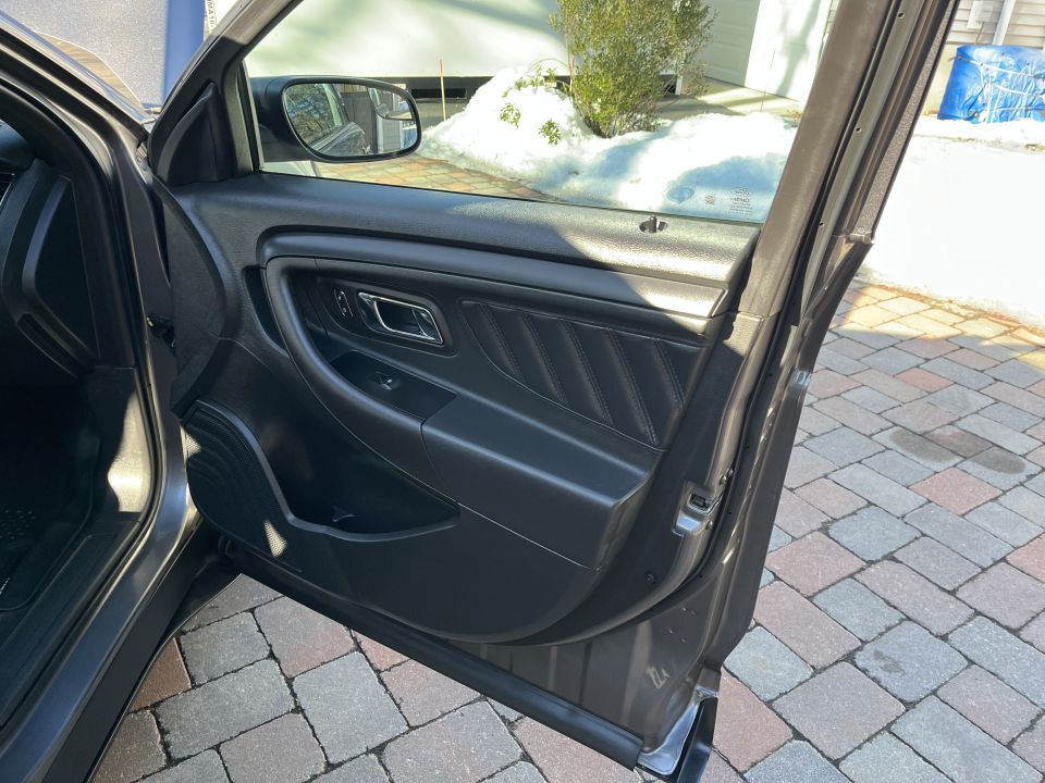 Open front door of a sedan showing the door panel and side mirror