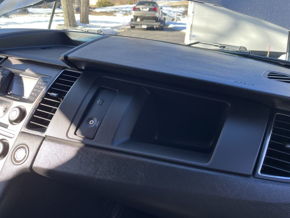Sedan passenger dashboard storage bin and audio controls